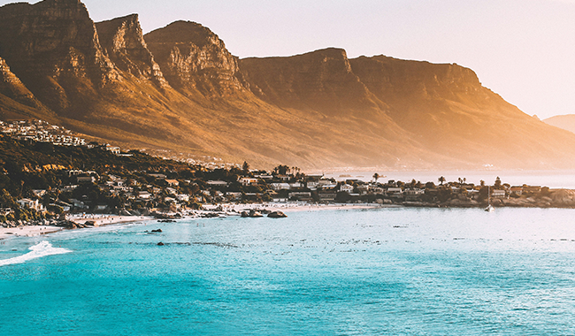 photography of buildings beside seashore and mountain during dayt